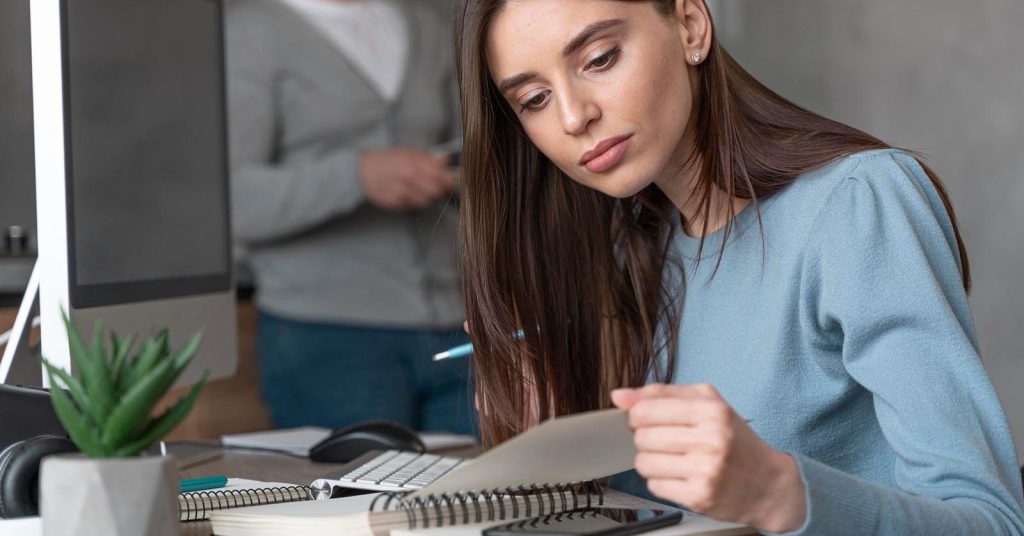 Woman reviewing a debt payoff plan and account records at her computer
