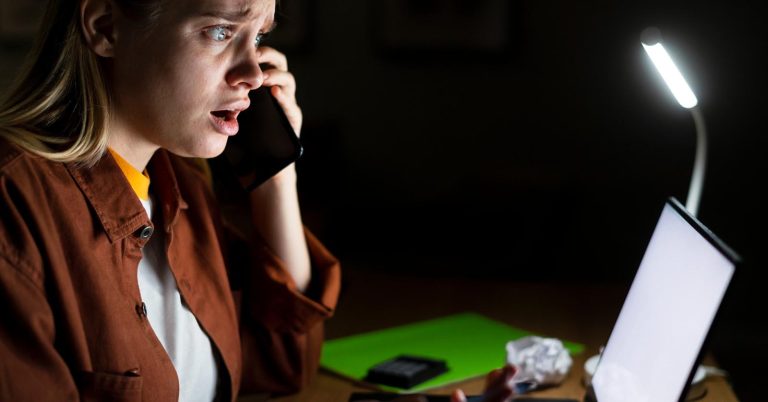 Woman reacting to a suspicious debt relief call while checking information on a laptop