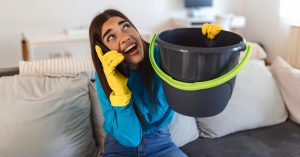 Woman holding a bucket while talking on the phone indoors