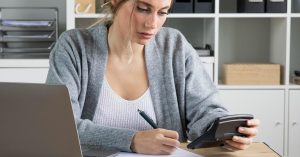 Self-employed woman reviewing income and expenses with a laptop and calculator