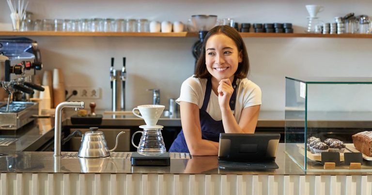 Cafe worker standing behind the counter beside a tablet