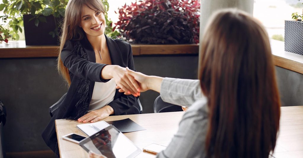 Job candidate shaking hands after reviewing a job offer and compensation package