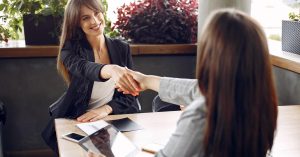 Job candidate shaking hands after reviewing a job offer and compensation package