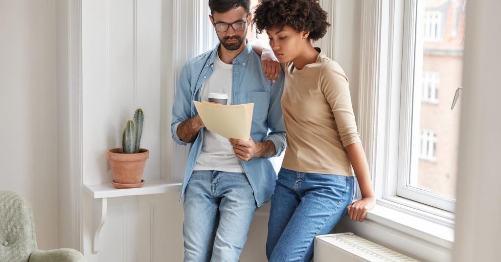 Two people reviewing documents together near a window