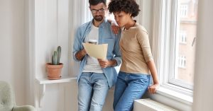 Two people reviewing documents together near a window
