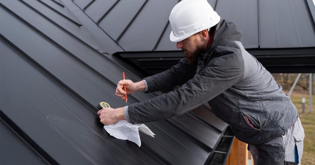 Person wearing a hard hat measuring a metal roof