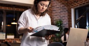 Woman reviewing financial documents beside a laptop