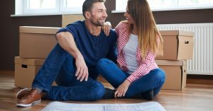 Couple sitting beside moving boxes with a house plan spread on the floor