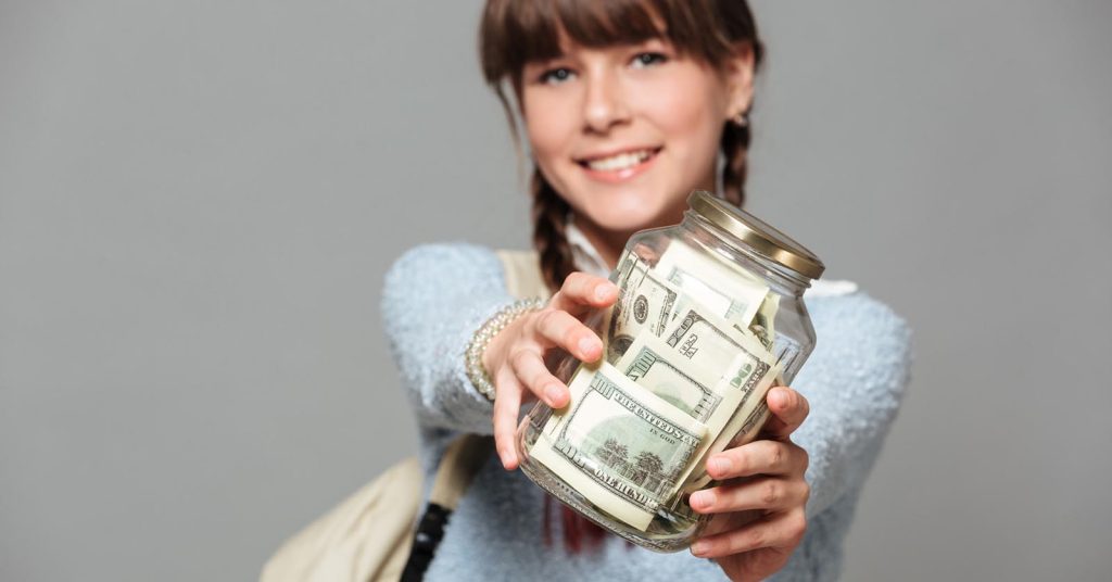 Woman holding a glass jar filled with dollar bills