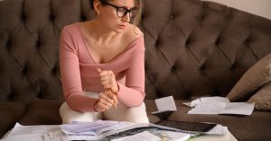 Woman reviewing household bills and cash at a coffee table