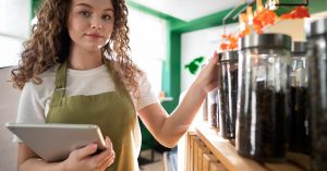Shop owner holding a tablet beside product jars