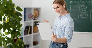 Woman holding a tablet in front of a chalkboard with English grammar notes