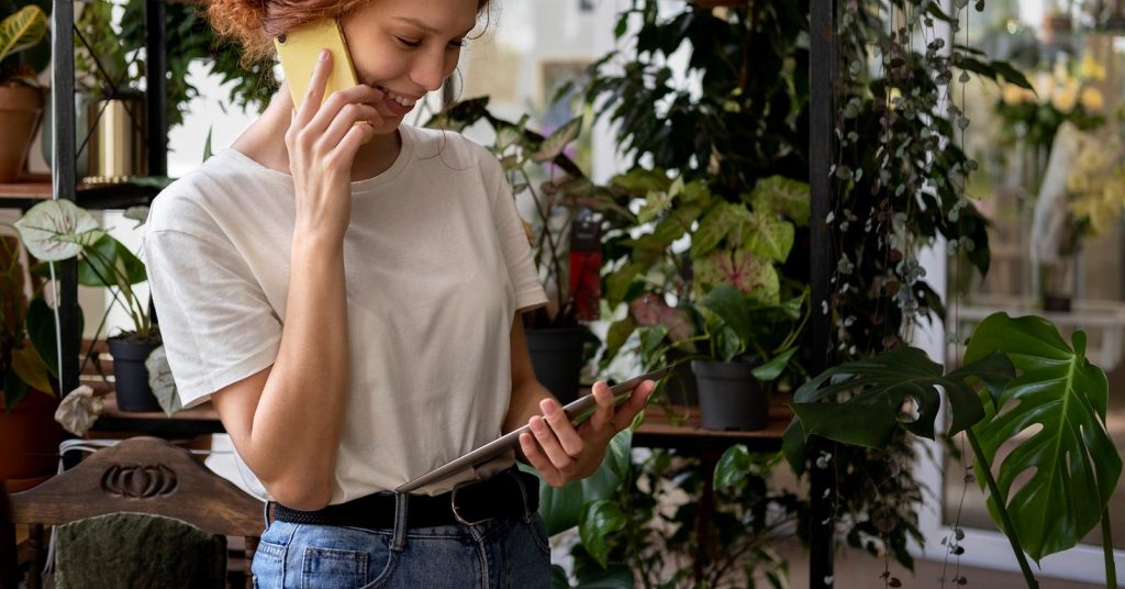 Plant shop owner talking on a phone while holding a tablet