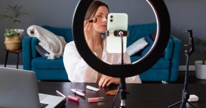 Woman applying makeup while recording with a smartphone and ring light