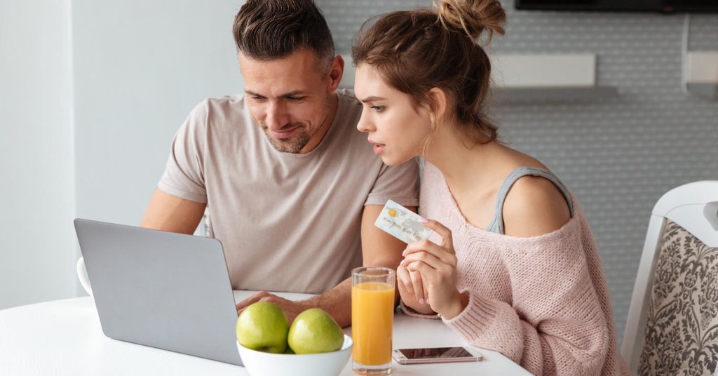 Couple using a laptop while holding a payment card