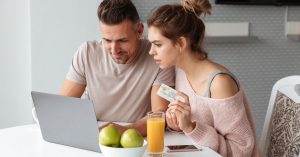 Couple using a laptop while holding a payment card