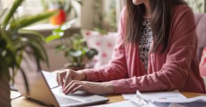 Woman reviewing financial documents while using a laptop