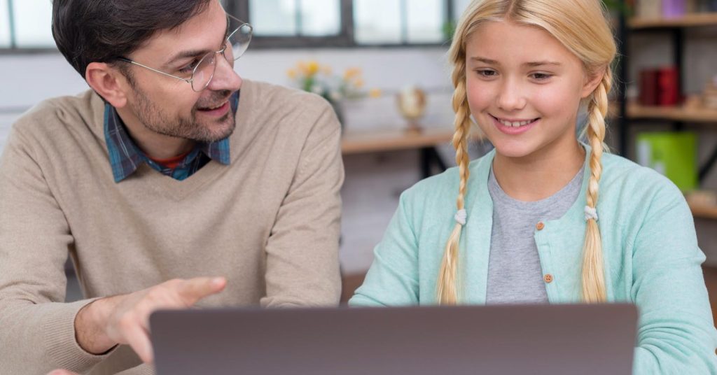 Father and daughter reviewing information on a laptop together