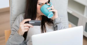 Woman holding a credit card while reviewing finances on a laptop