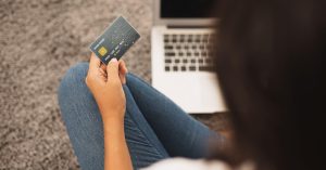 Woman holding a credit card while reviewing her account on a laptop