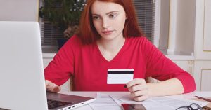 Woman holding a credit card while reviewing an application on a laptop