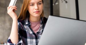 Woman using a laptop while holding a credit card