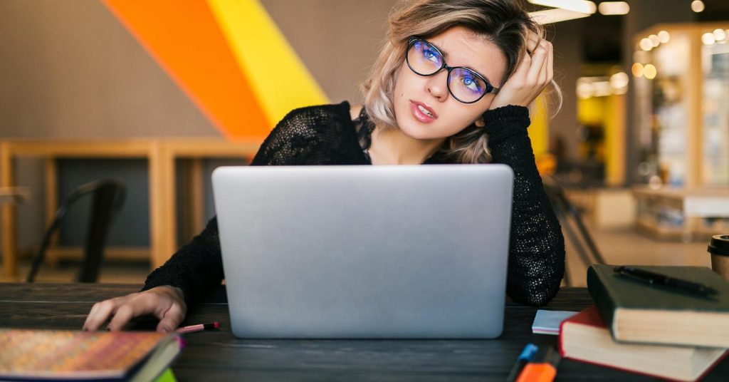 Woman reviewing a debt payoff plan on her laptop while protecting money set aside for emergencies