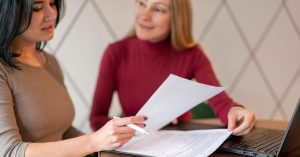 Two women reviewing rental paperwork beside a laptop