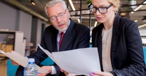 Two people comparing financial documents together