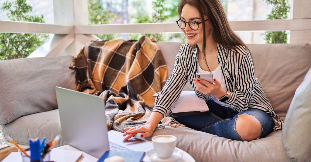 Woman exploring side hustle ideas using a laptop and smartphone at home