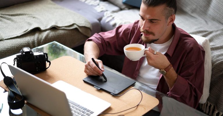 Person working on a creative side hustle from home using a laptop and drawing tablet