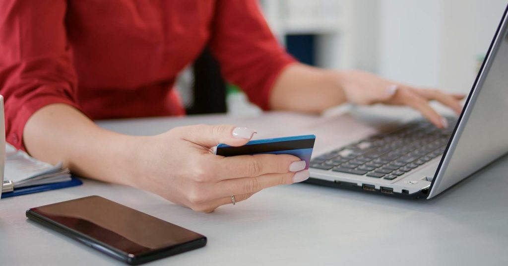 Woman holding a credit card while using a laptop