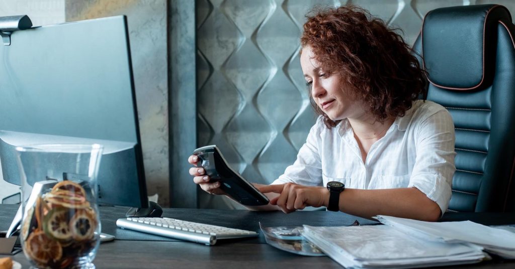 Woman using a calculator while reviewing paperwork at a desk