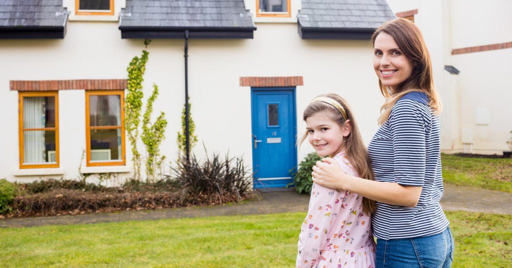 Woman and child standing in front of a house