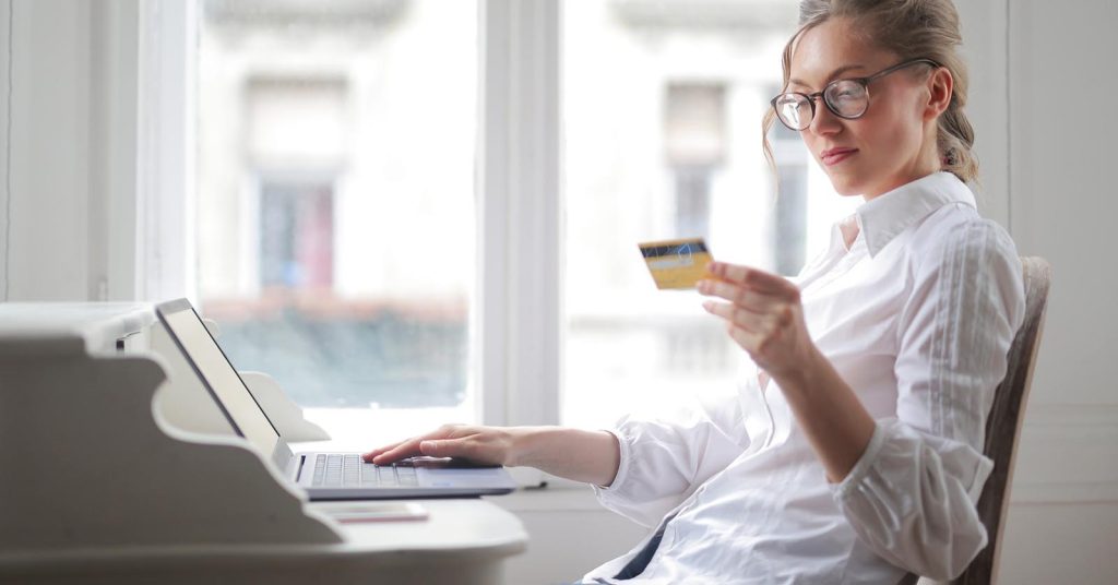 Woman holding a credit card while using a laptop