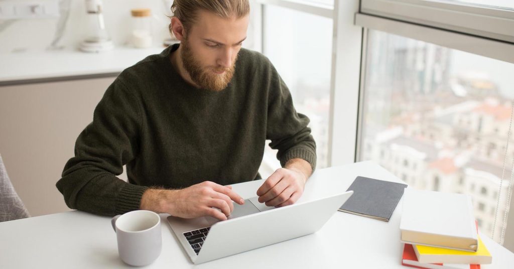 Man reviewing new savings and investment goals on a laptop after paying off debt