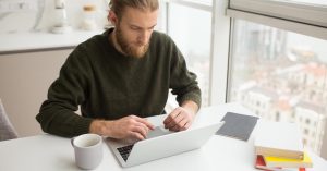 Man reviewing new savings and investment goals on a laptop after paying off debt