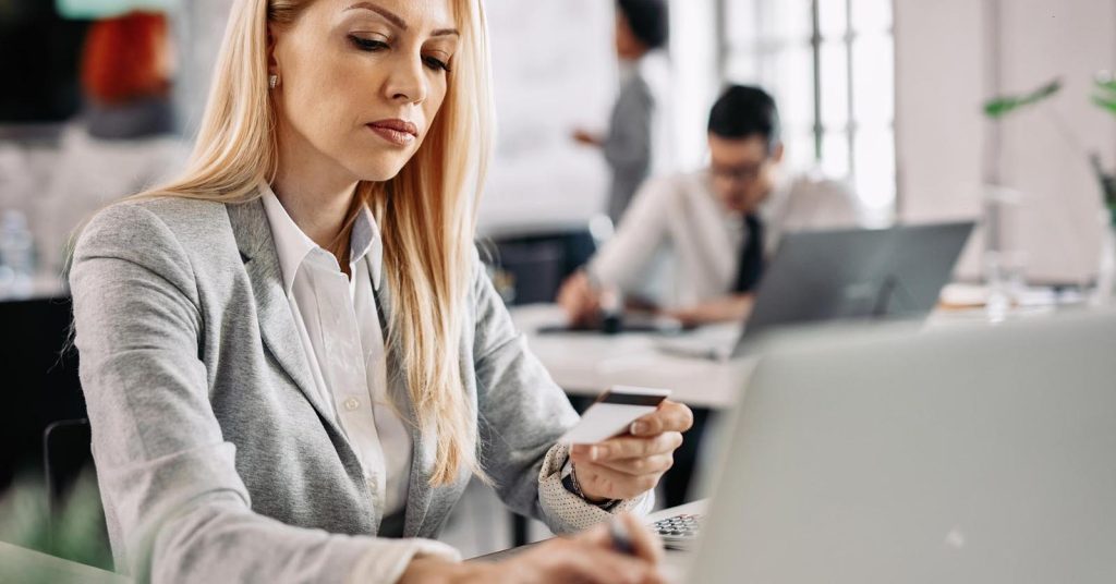Businesswoman holding a credit card while working on a laptop