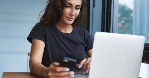 Woman comparing financial information on a smartphone and laptop