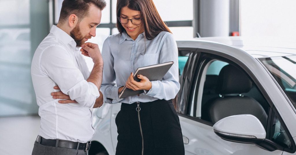 Driver discussing car insurance coverage and policy details beside a vehicle