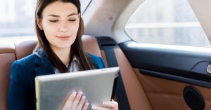 Woman using a tablet while sitting in the back seat of a car