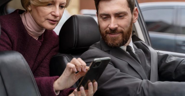 Driver and passenger looking at a smartphone inside a car