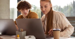 Two adults working side by side on laptops