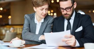 Two professionals comparing documents at a table