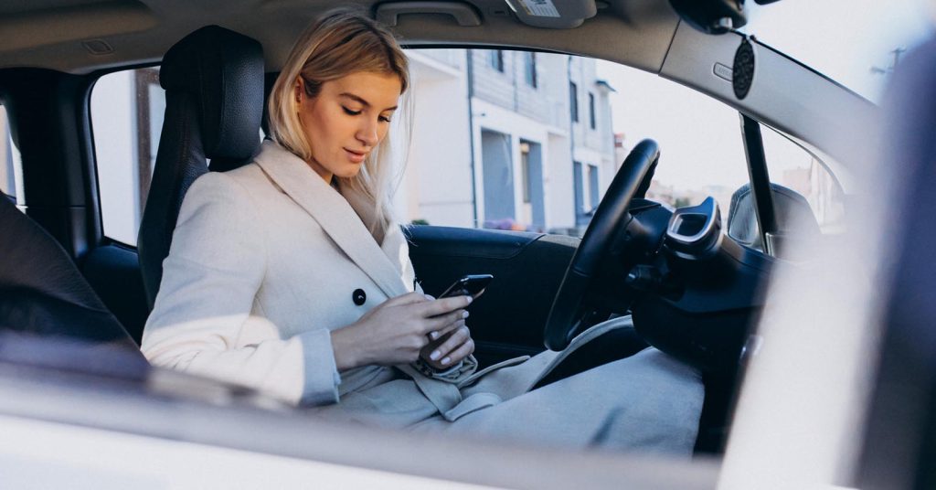 Driver checking a telematics insurance app while parked in a car