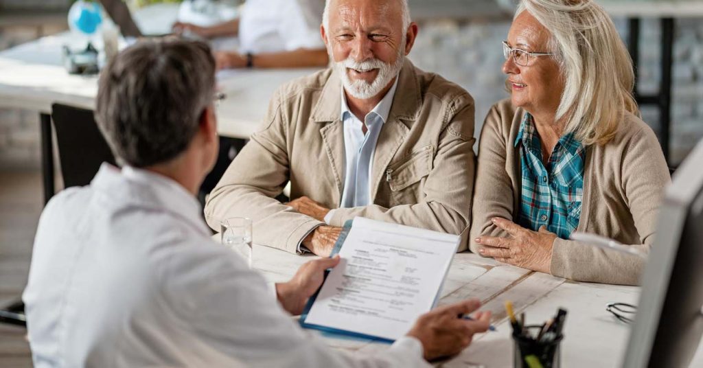 Older couple reviewing life insurance documents with an adviser
