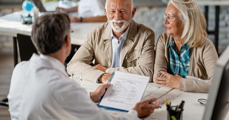 Older couple reviewing life insurance documents with an adviser