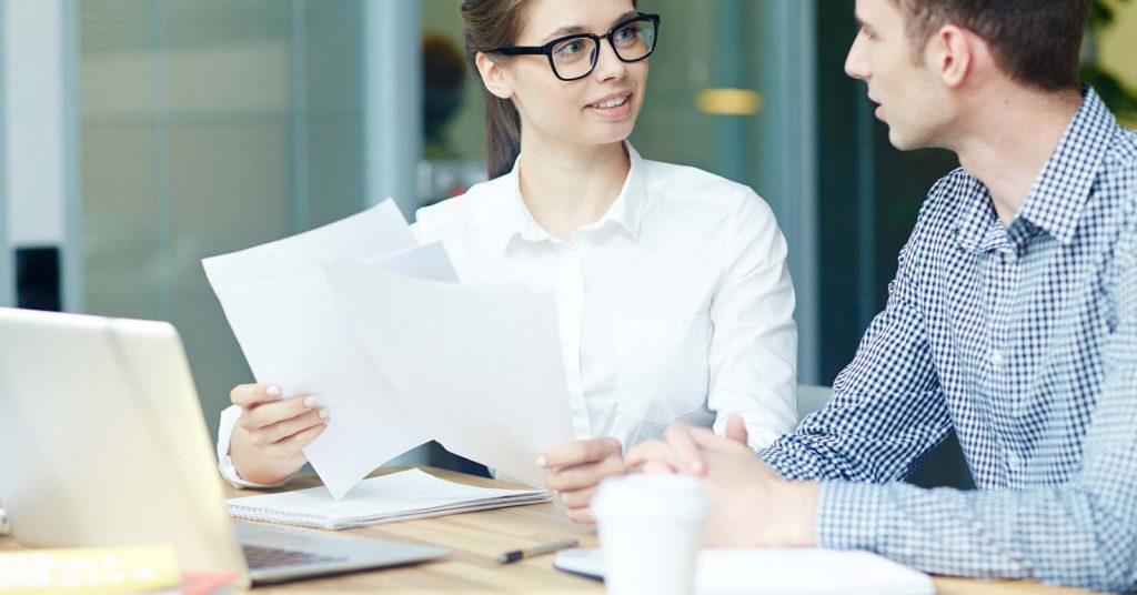 Adviser and client reviewing documents beside a laptop