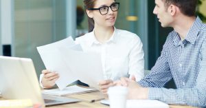 Adviser and client reviewing documents beside a laptop