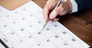 Person marking dates on a paper calendar to plan an insurance term